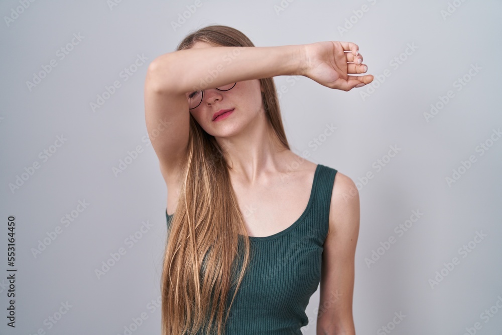 Young caucasian woman standing over white background covering eyes with arm, looking serious and sad. sightless, hiding and rejection concept Young caucasian woman standing over white background covering eyes with arm, looking serious and sad. sightless, hiding and rejection concept