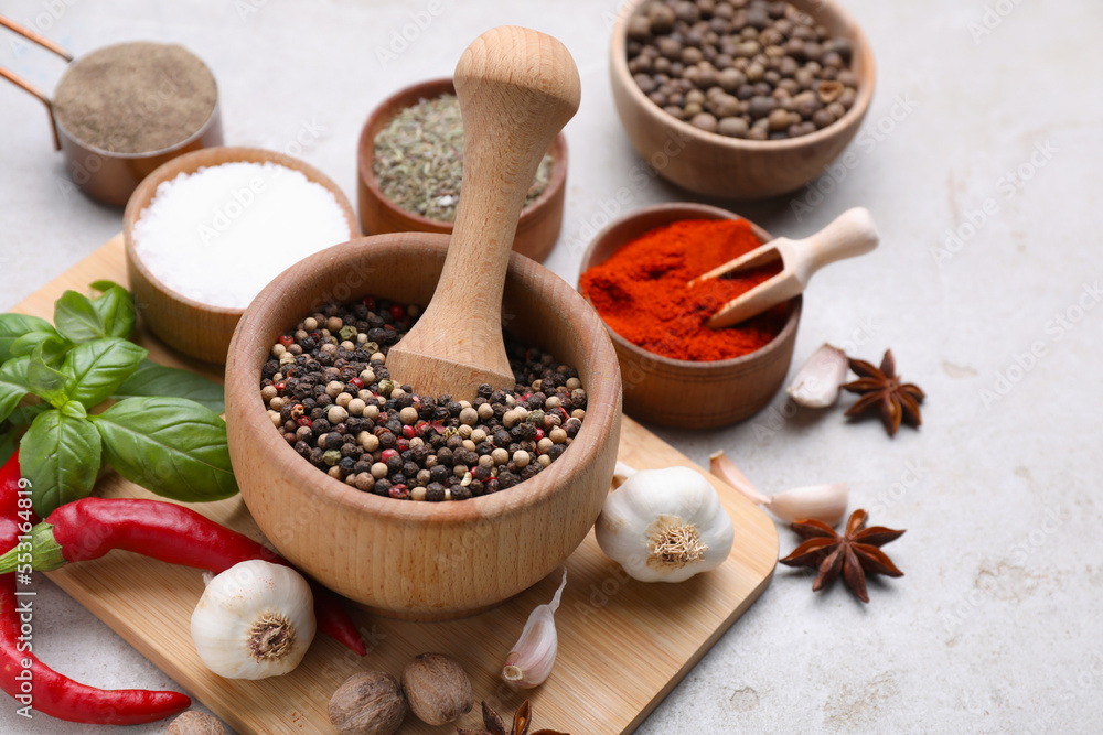 Mortar with pestle and different spices on light grey table Mortar with pestle and different spices on light grey table