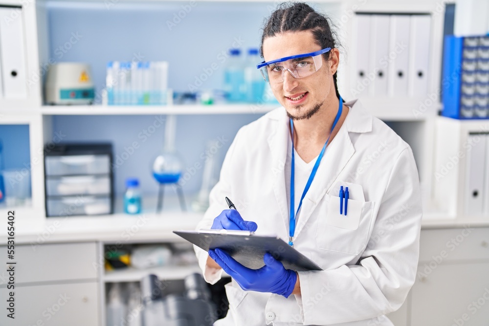 Young man wearing scientist uniform write on clipboard at laboratory