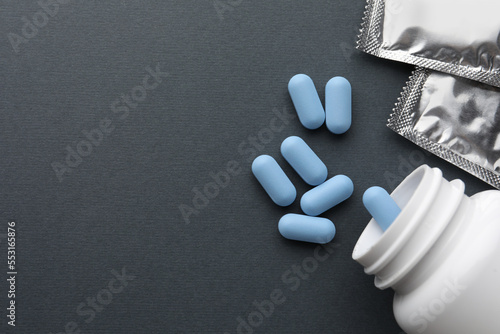 Pills and medical bottle on dark gray background, flat lay with space for text. Potency problem photo