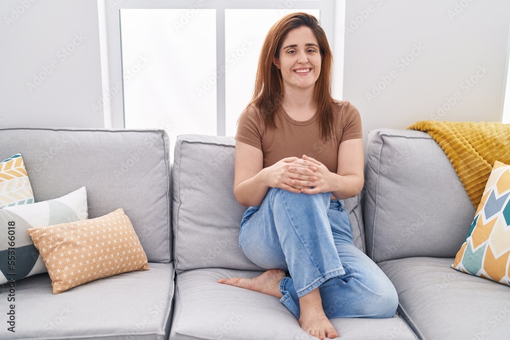 Young woman smiling confident sitting on sofa at home Young woman smiling confident sitting on sofa at home