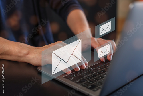 hands using Laptop typing on keyboard and surfing the internet on office table with email icon, email marketing concept, send e-mail or news letter, online working internet network. 