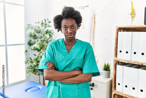 African young physiotherapist woman working at pain recovery clinic skeptic and nervous, frowning upset because of problem. negative person.