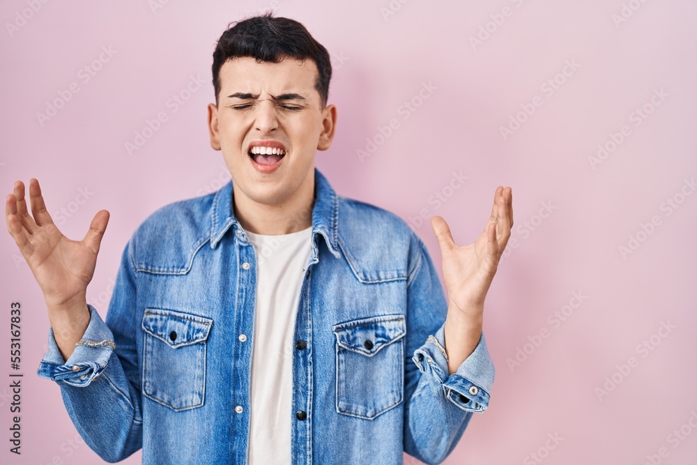 Non binary person standing over pink background celebrating mad and crazy for success with arms raised and closed eyes screaming excited. winner concept Non binary person standing over pink background celebrating mad and crazy for success with arms raised and closed eyes screaming excited. winner concept