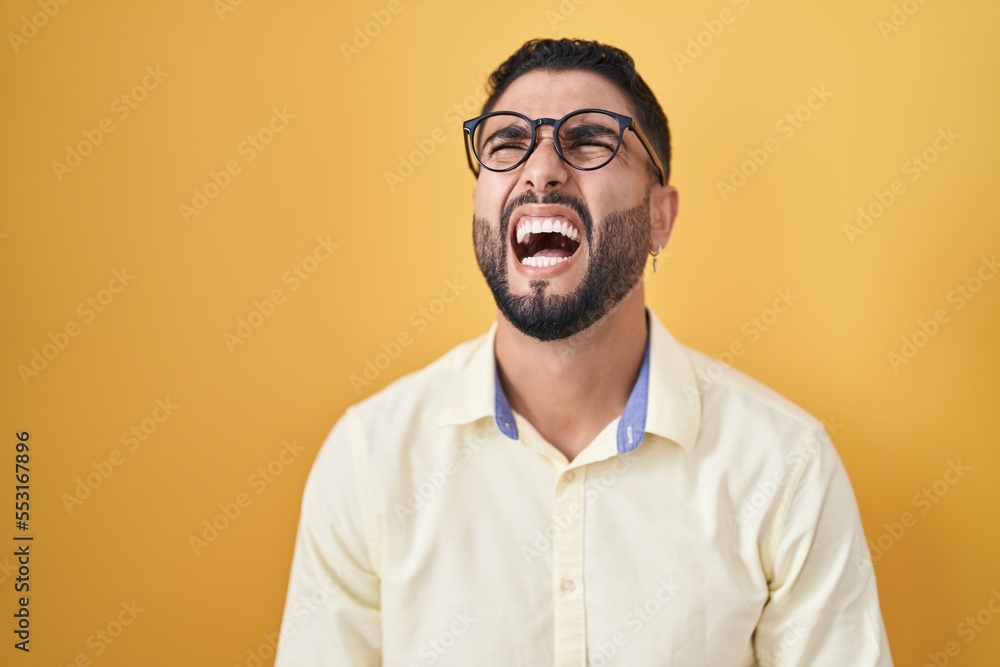 Hispanic young man wearing business clothes and glasses angry and mad screaming frustrated and furious, shouting with anger. rage and aggressive concept. Hispanic young man wearing business clothes and glasses angry and mad screaming frustrated and furious, shouting with anger. rage and aggressive concept.