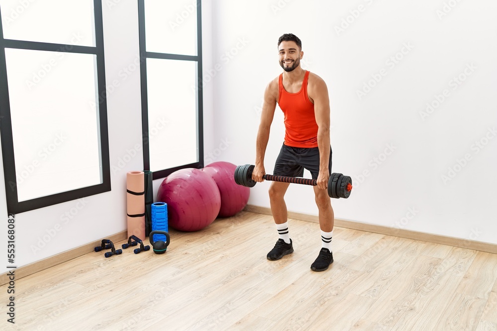Obraz premium Young arab man smiling confident training with dumbbells at sport center