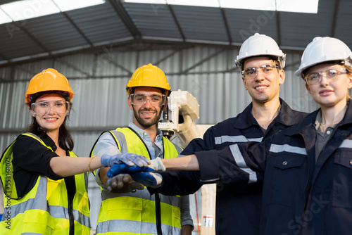 Group of male and female engineer worker working together and control automatic robot arm system welding in the industry factory