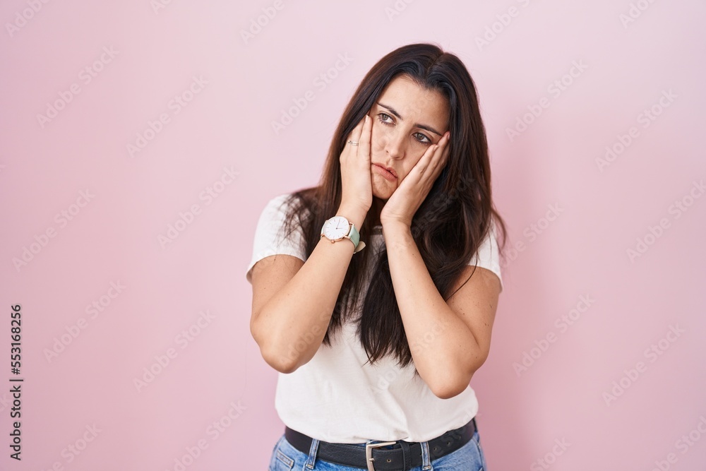 Young brunette woman standing over pink background tired hands covering face, depression and sadness, upset and irritated for problem Young brunette woman standing over pink background tired hands covering face, depression and sadness, upset and irritated for problem