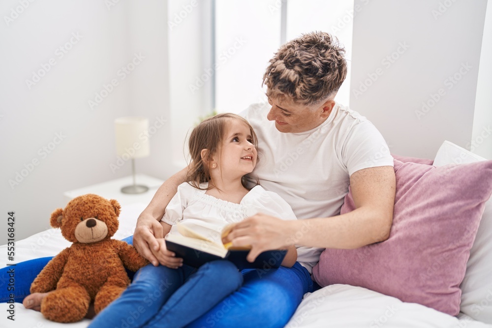 Father and daughter father and daughter reading book holding teddy bear at bedroom
