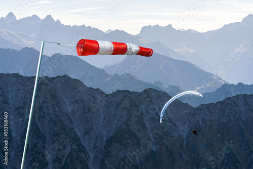 Windbag and Paraglider flying above Mountain Silhouette. Bad wind conditions. Allgaeu, Oberstdorf, Alps, Germany. Concept for creative business ideas.