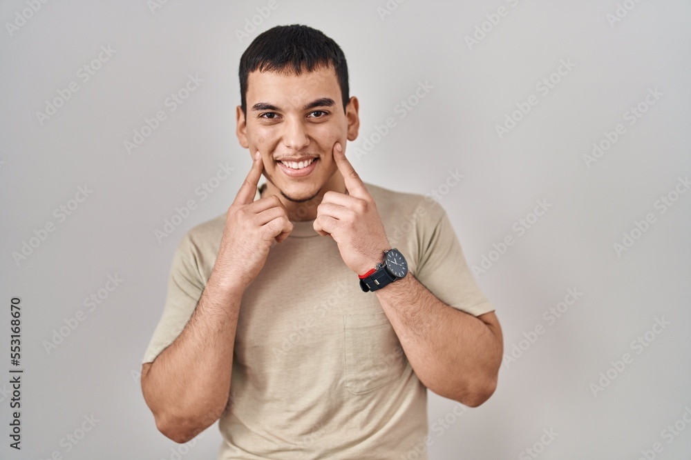 Young arab man wearing casual t shirt smiling with open mouth, fingers pointing and forcing cheerful smile Young arab man wearing casual t shirt smiling with open mouth, fingers pointing and forcing cheerful smile