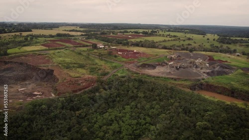 A dynamic wide-angle aerial footage of an open stone quarry with a moving wheel loader. It is an open-pit type of mining where rocks, sand, or minerals are extracted from the surface of the Earth.  photo