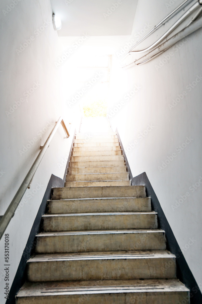 Fototapeta premium Staircase going up to white light door