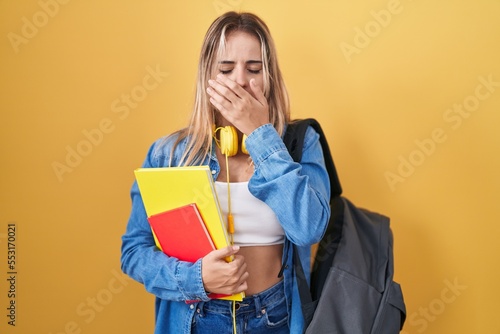 Young blonde woman wearing student backpack and holding books bored yawning tired covering mouth with hand. restless and sleepiness.