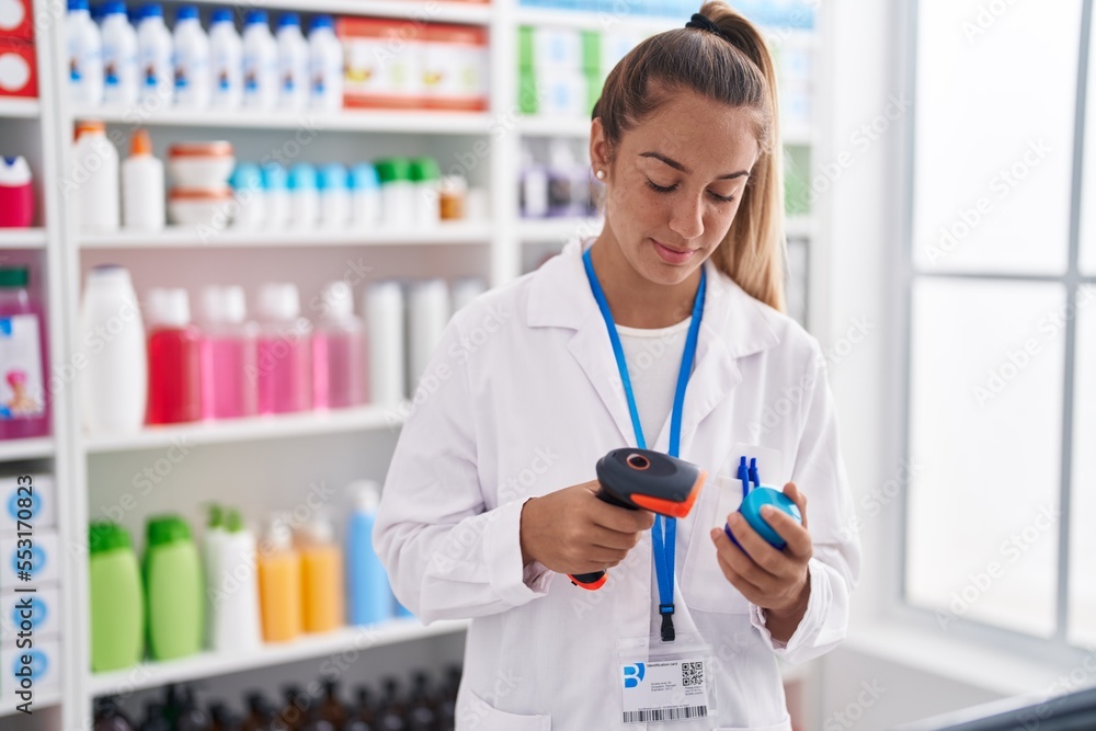 Young beautiful hispanic woman pharmacist scanning pills bottle at pharmacy