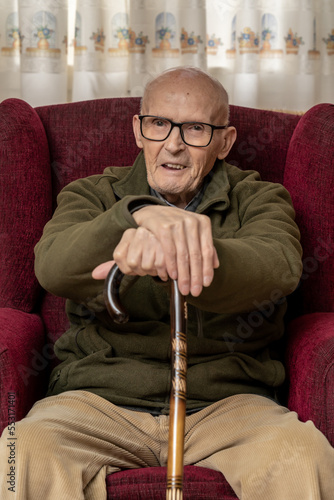 Padre con su hija haciendo videollamada al nieto, persona mayor con su hija sentado en el sillón de casa