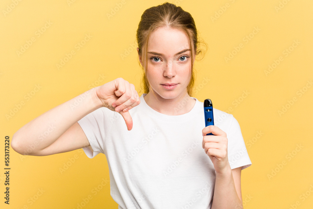 Young cute woman holding a vaper isolated on yellow background showing a dislike gesture, thumbs down. Disagreement concept. Young cute woman holding a vaper isolated on yellow background showing a dislike gesture, thumbs down. Disagreement concept.