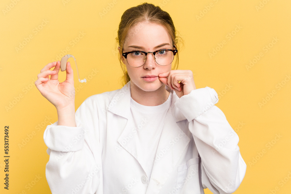 Young otorhinolaryngologist caucasian woman isolated on yellow background with fingers on lips keeping a secret. Young otorhinolaryngologist caucasian woman isolated on yellow background with fingers on lips keeping a secret.