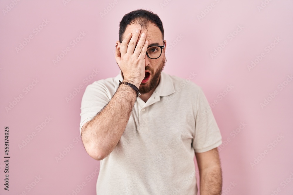 Plus size hispanic man with beard standing over pink background yawning tired covering half face, eye and mouth with hand. face hurts in pain. Plus size hispanic man with beard standing over pink background yawning tired covering half face, eye and mouth with hand. face hurts in pain.