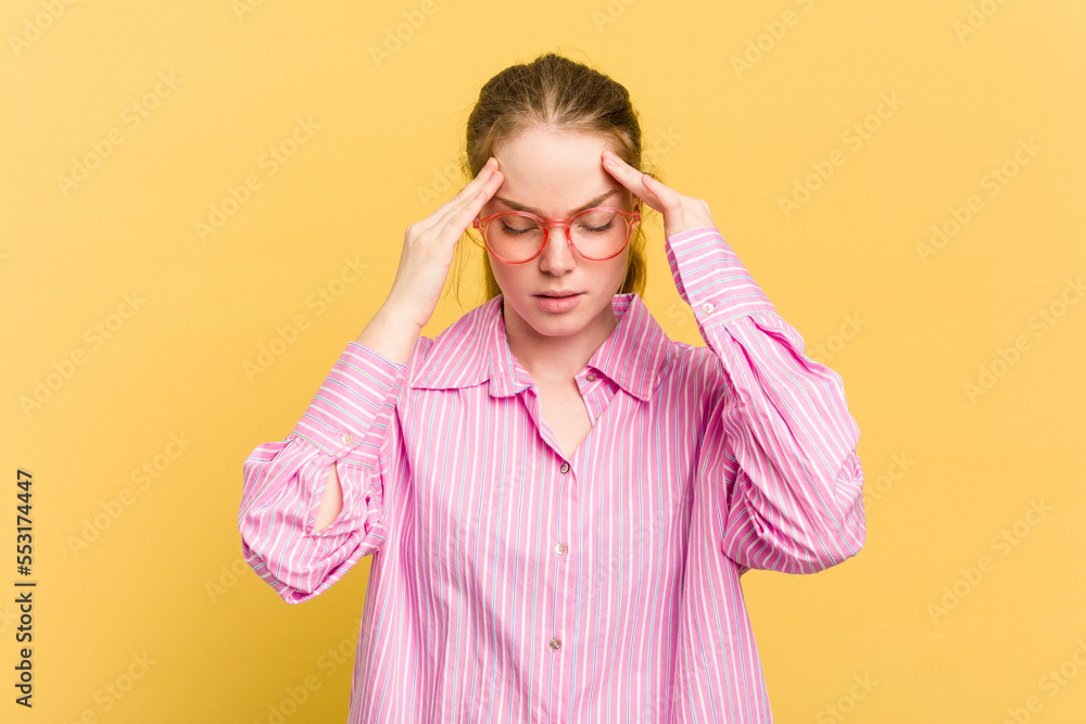 Young caucasian redhead woman isolated on yellow background having a head ache, touching front of the face. Young caucasian redhead woman isolated on yellow background having a head ache, touching front of the face.