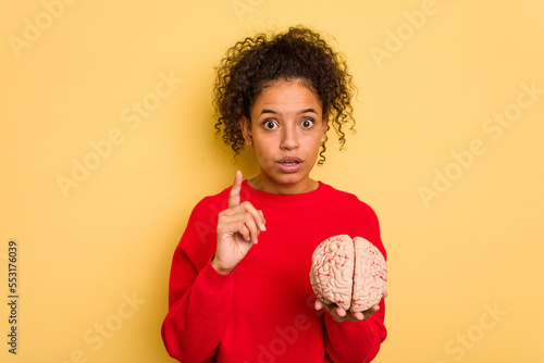 Young brazilian woman holding a brain model isolated having an idea, inspiration concept.