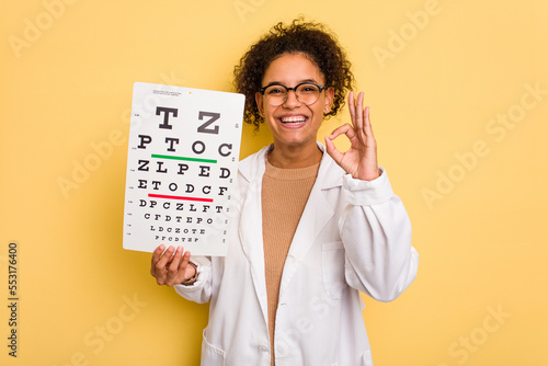 Young brazilian oculist woman isolated cheerful and confident showing ok gesture. photo