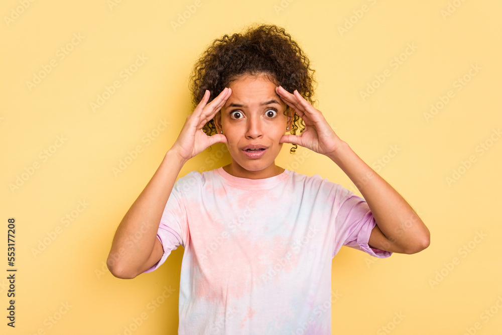 Young Brazilian curly hair cute woman isolated on yellow background receiving a pleasant surprise, excited and raising hands. Young Brazilian curly hair cute woman isolated on yellow background receiving a pleasant surprise, excited and raising hands.