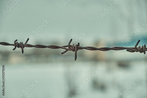 Old barbed wire on a concrete fence large with snow in winter close-up Selective focus