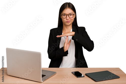 Young business asian woman sitting on a table isolated showing a timeout gesture. photo