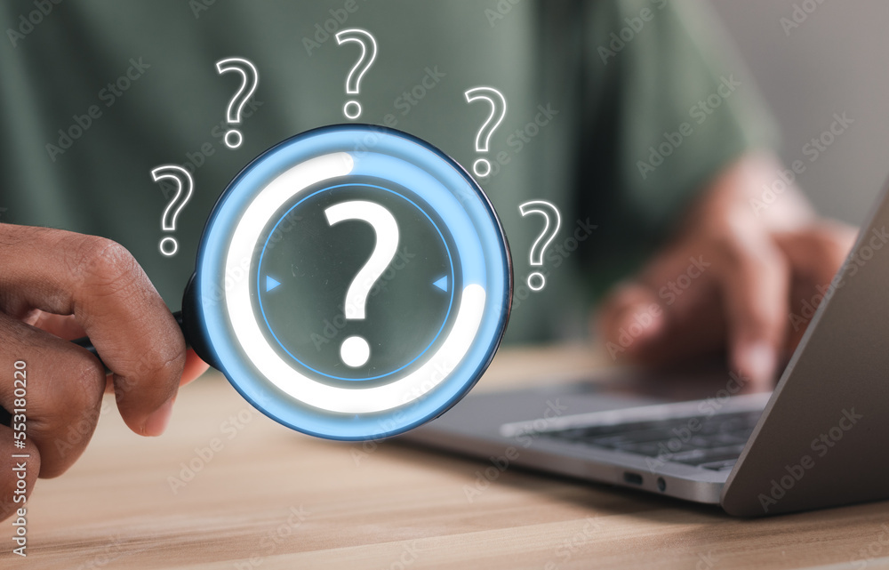 Businessman using magnifying glass to look at question mark on virtual screen interface. Question marks concept. Businessman using magnifying glass to look at question mark on virtual screen interface. Question marks concept.