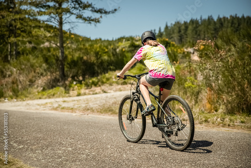 outdoor portrait of a white happy girl riding a bike on natural background. High quality photo