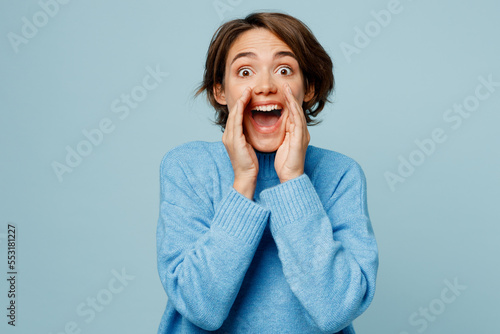 Картината върху платно Young fun caucasian woman wear knitted sweater scream sharing hot news about sales discount with hands near mouth isolated on plain pastel light blue cyan background studio