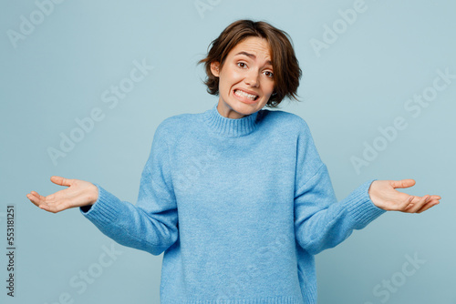 Tablou pe pânză Young caucasian woman wear knitted sweater shrugging shoulders looking puzzled, have no idea spread hands isolated on plain pastel light blue cyan background studio portrait