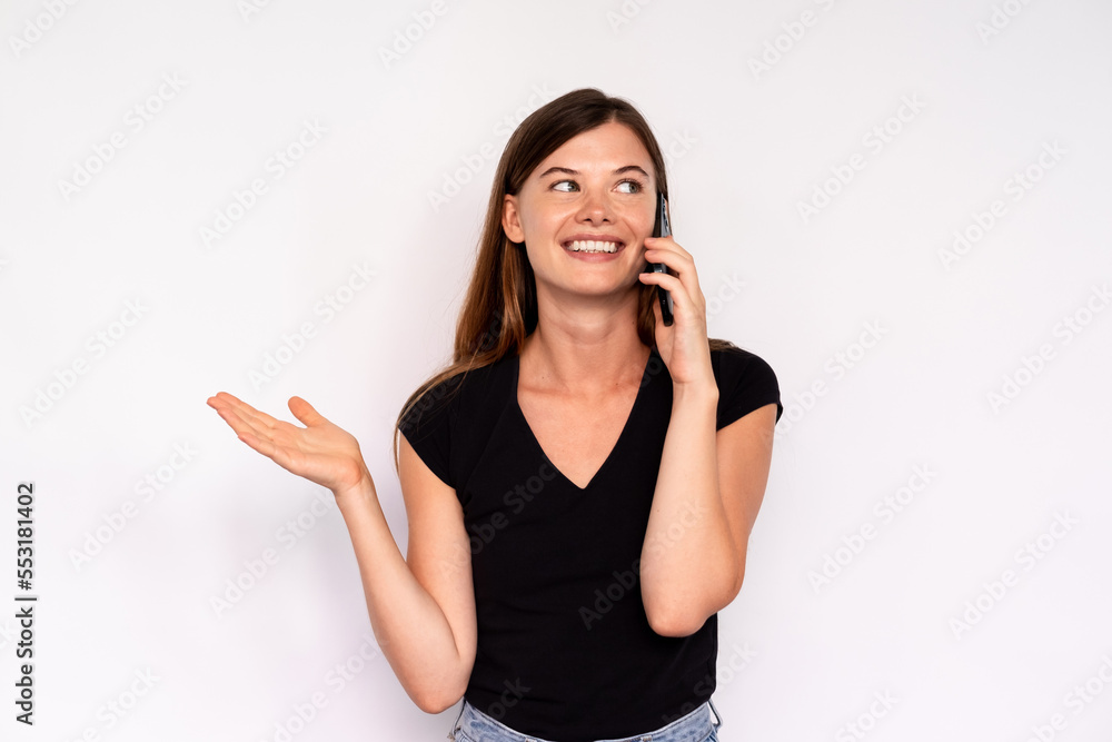 Portrait of happy young woman calling friend on mobile phone over white background. Caucasian lady wearing black T-shirt and jeans looking away and smiling. Mobile communication concept Portrait of happy young woman calling friend on mobile phone over white background. Caucasian lady wearing black T-shirt and jeans looking away and smiling. Mobile communication concept