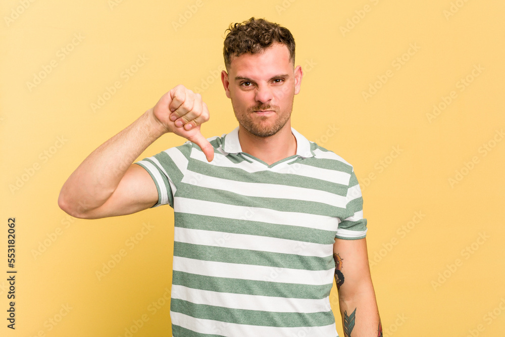 Obraz premium Young caucasian handsome man isolated on yellow background showing thumb down, disappointment concept.