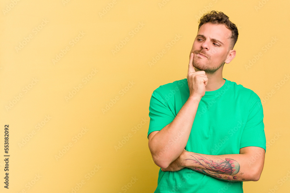 Young caucasian handsome man isolated on yellow background looking sideways with doubtful and skeptical expression. Young caucasian handsome man isolated on yellow background looking sideways with doubtful and skeptical expression.