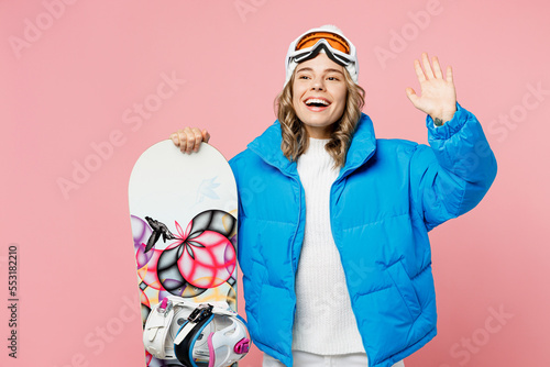 Snowboarder happy smiling woman wear blue suit goggles mask hat ski padded jacket waving hand look aside isolated on plain pastel pink background Winter extreme sport hobby weekend trip relax concept