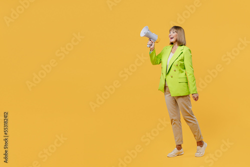 Full body elderly woman 50s years old wearing green jacket white t-shirt hold scream in megaphone announces discounts sale Hurry up isolated on plain yellow background studio People lifestyle concept © ViDi Studio