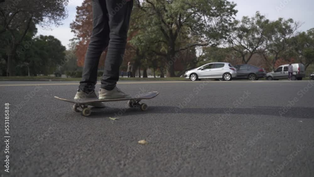 Close up skateboard. Skater riding on the paved street close to park. Close up skateboard. Skater riding on the paved street close to park.