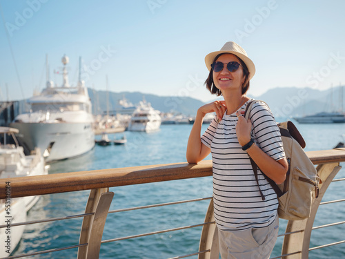 Marmaris is resort town on Turkish Riviera, also known as Turquoise Coast. Marmaris is great place for sailing and diving. Asian woman with hat walking on pier in harbor.