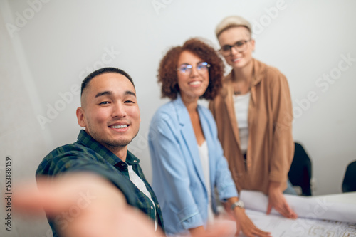 Cheerful draftsman photographing himself and coworkers at the staff meeting