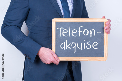 Vertriebsmitarbeiter mit einer Tafel auf der Telefonakquise steht
