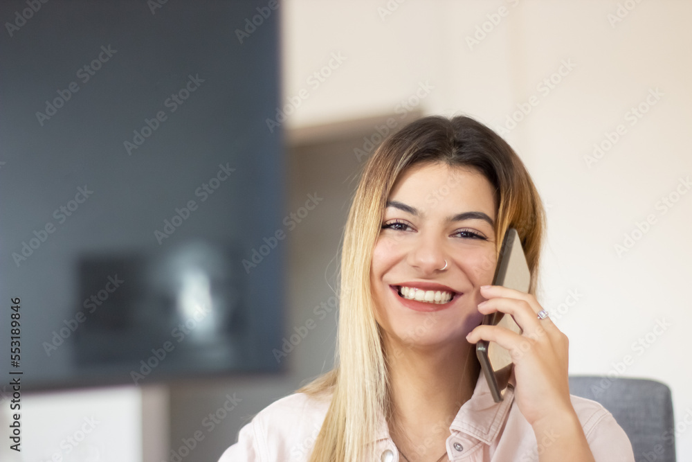 Portrait shot of charming Caucasian lady looking at camera and smiling. Successful businesswoman talking on phone while working in office. Success, business, youth concept Portrait shot of charming Caucasian lady looking at camera and smiling. Successful businesswoman talking on phone while working in office. Success, business, youth concept