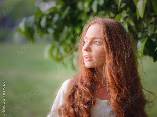 Beauty Woman Face With Healthy Skin And Green Plant at sunset time outdoor. Healthy lifestyle, beauty, natural concept. Melancholic beautiful portrait