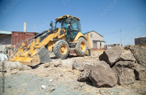 Excavator works at the construction site. Focus on stones
