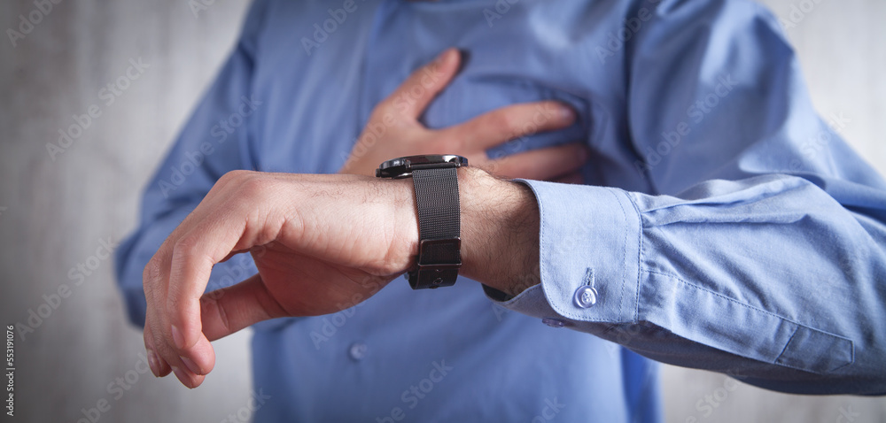 Caucasian man looking in wrist watch. Checking pulse in heart