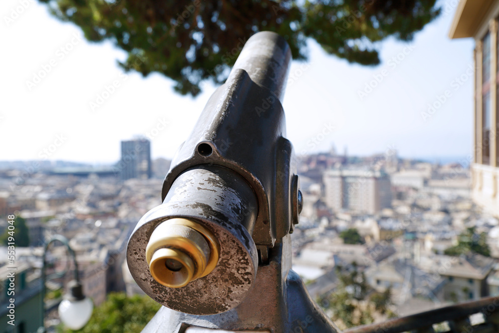 In the foreground a coin operated telescope in the background Genoa panoramic view, Italy In the foreground a coin operated telescope in the background Genoa panoramic view, Italy