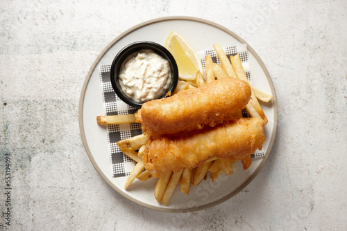 top view shot of fish and chips with buttermilk ranch dipping sauce all placed in a white plate