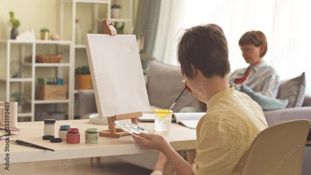 Talented girl with down syndrome painting on canvas while staying with mother at home Talented girl with down syndrome painting on canvas while staying with mother at home
