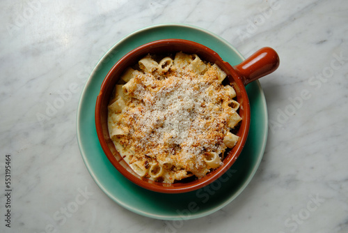 Top shot of guanciale and four cheese truffle mac in a red mug on a green plate photo